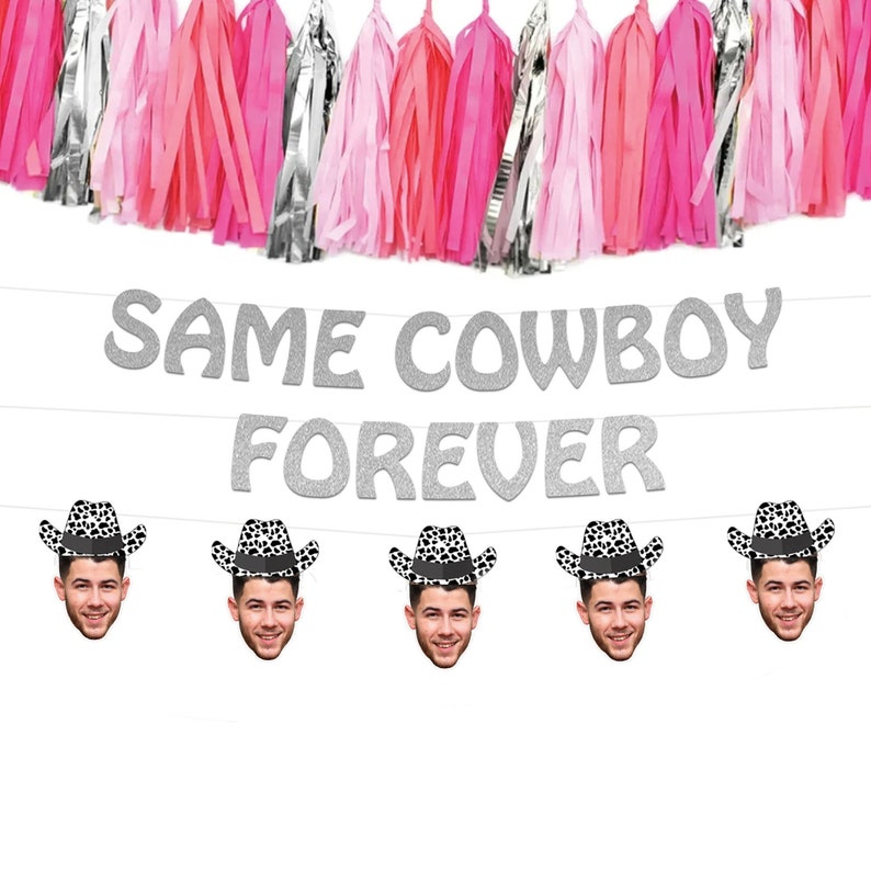 May include: A festive party banner with the text "SAME COWBOY FOREVER" in silver glitter letters. Below, five face cutouts wear cowboy hats. The background features pink, silver, and red paper tassels, perfect for a bachelorette party.