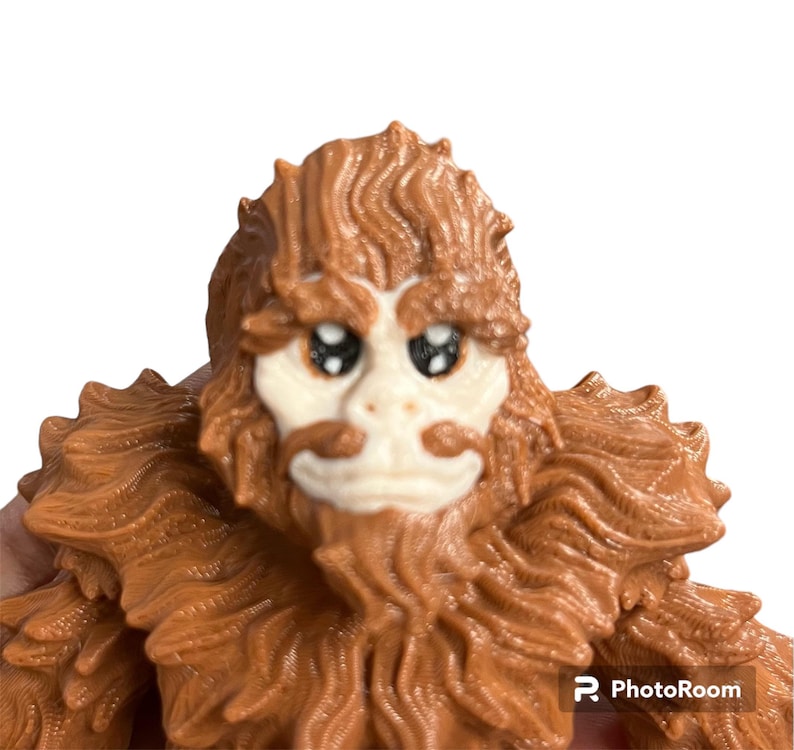 May include: A brown, furry creature with a white face and large, black eyes. The creature has a long, brown beard and a small, white nose.
