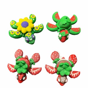 May include: Four colorful turtle figurines with different designs. One turtle has a yellow flower on its back, another has a red strawberry, and the other two have green leaves.