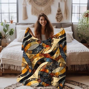 May include: A colorful throw blanket with an abstract stained glass design. The blanket features a mosaic pattern with shades of gold, orange, blue, and black. The design is composed of curved lines and geometric shapes, creating a visually appealing textile.
