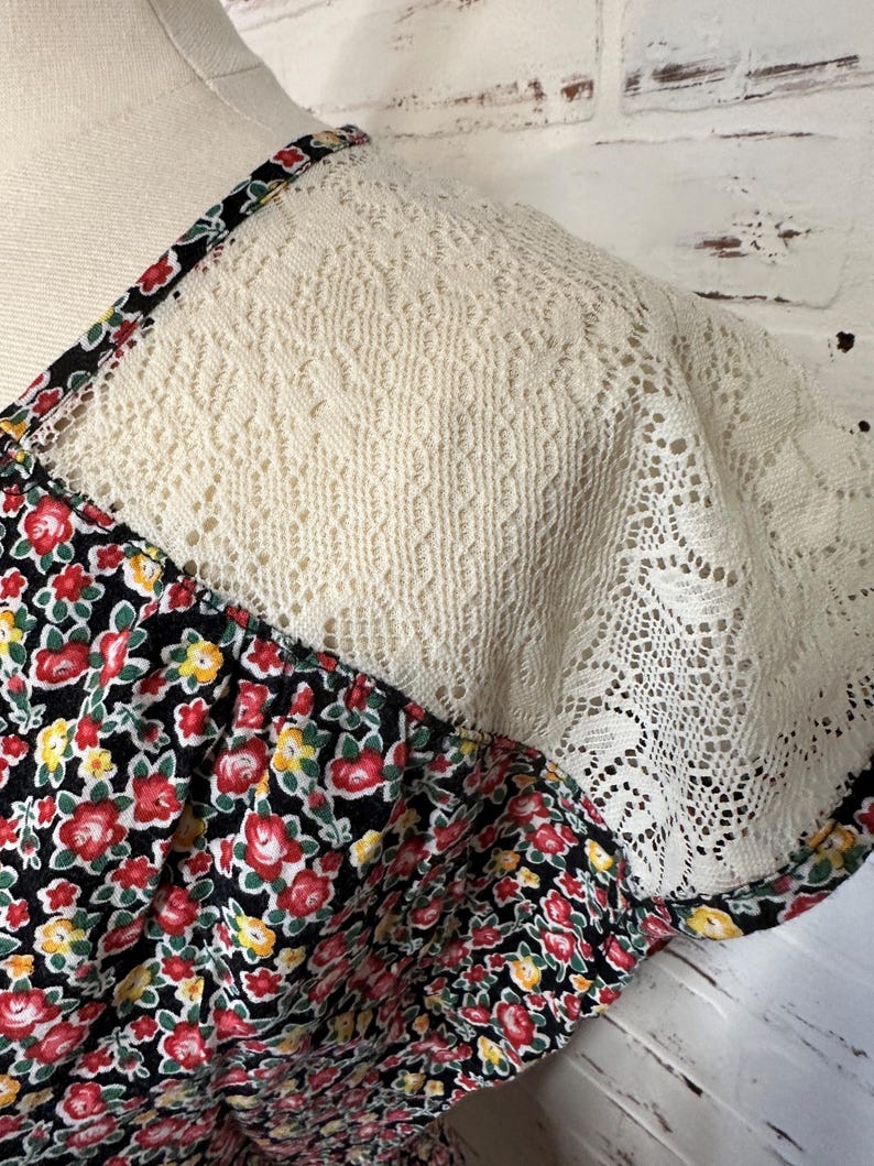 May include: A black dress with a floral print and a white lace overlay on the shoulders.