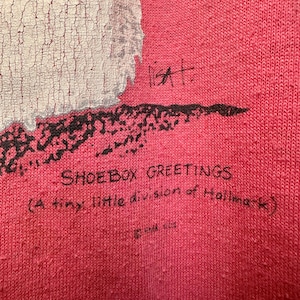 May include: Red t-shirt with a white and black graphic print of a snowman. The text "Shoebox Greetings (A tiny little division of Hallmark)" is printed on the bottom of the shirt.