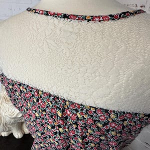 May include: A black dress with a floral print and a lace overlay at the neckline. The dress has a fitted bodice and a flowy skirt.