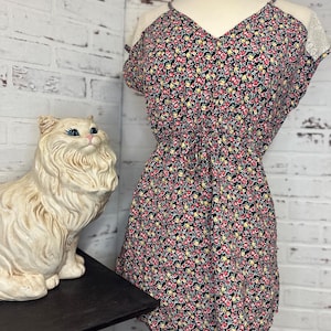 May include: A black floral print dress with a V-neckline and lace trim on the shoulders. The dress has a fitted bodice and a flowy skirt.