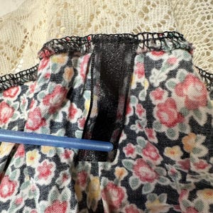 May include: Close-up of a black and white floral fabric with a black ribbon sewn along the top edge. The fabric has a white lace trim.