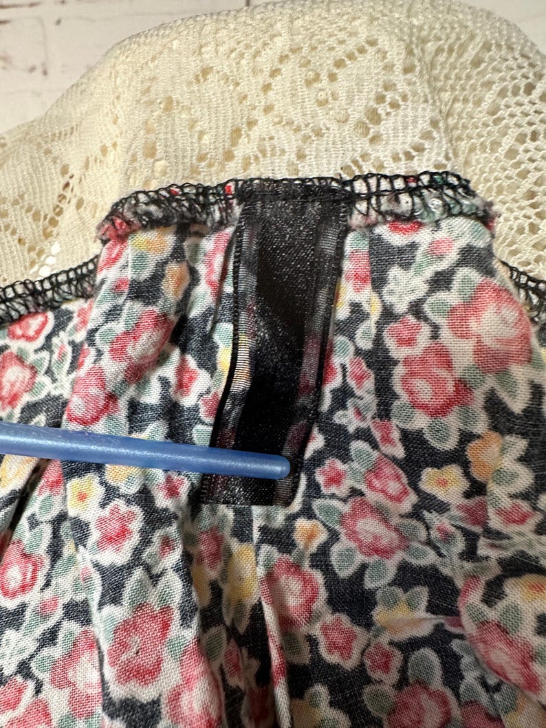 May include: Close-up of a black and white floral fabric with a black ribbon sewn along the top edge. The fabric has a white lace trim.