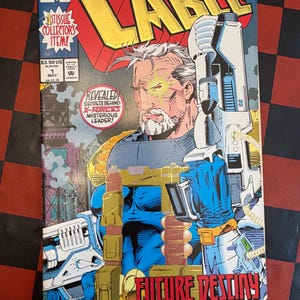 May include: A comic book cover for "Cable" featuring a futuristic character with a cybernetic eye and holding a large weapon. The cover has the text "FUTURE DESTINY" and "REVEALED! SECRETS BEHIND X-FORCE'S MYSTERIOUS LEADER!"