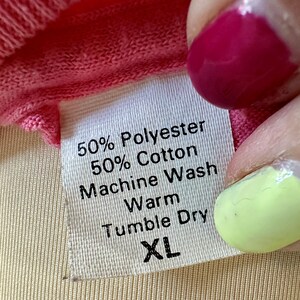 May include: White care label with black text. The label reads "50% Polyester 50% Cotton Machine Wash Warm Tumble Dry XL".