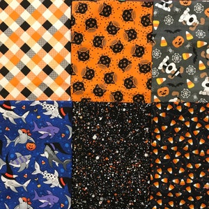 K&ouml;nnte beinhalten: Ein Patchwork aus quadratischen Stoffen zum Thema Halloween. Muster sind orange und schwarzes Karomuster, schwarze Katzen auf Orange, Halloween-Hunde, Haie mit Hexenh&uuml;ten, wei&szlig;e Sprenkel auf Schwarz und Zuckermais.