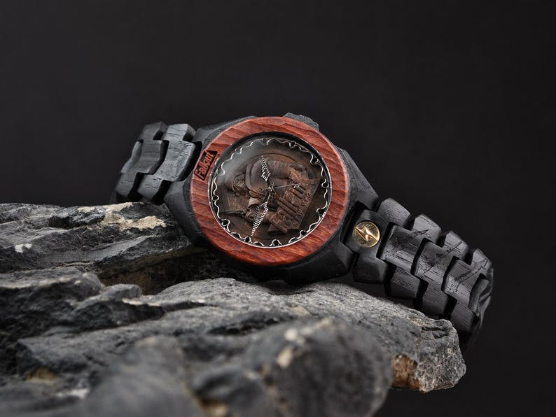 May include: A wristwatch featuring a dark black wooden link band and a circular reddish-brown wooden bezel. The watch face displays a detailed relief of a character and the word Fallout. A small gold-coloured lightning bolt emblem is on the band.
