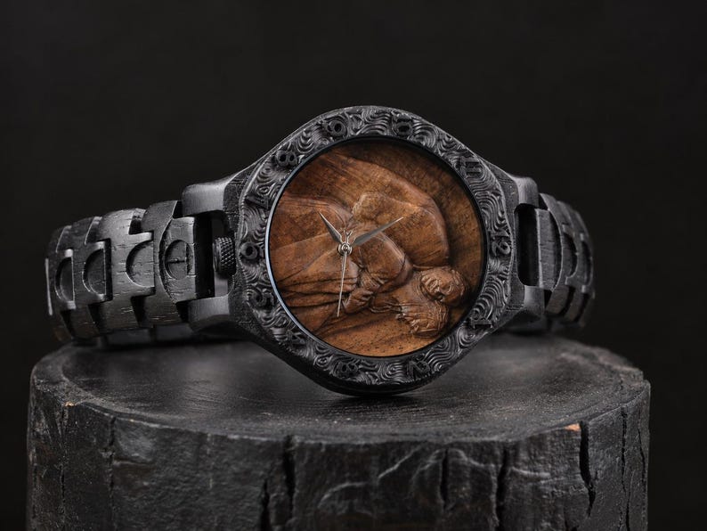 May include: A wristwatch featuring a dark black wooden band and a matching black wooden bezel with intricate carved details. The watch face displays a natural brown wood grain background with a three-dimensional carved relief of a human figure.