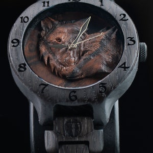 May include: A black wooden wristwatch with a wolf design on the face. The watch has a black leather strap and a gold-coloured hour and minute hand.