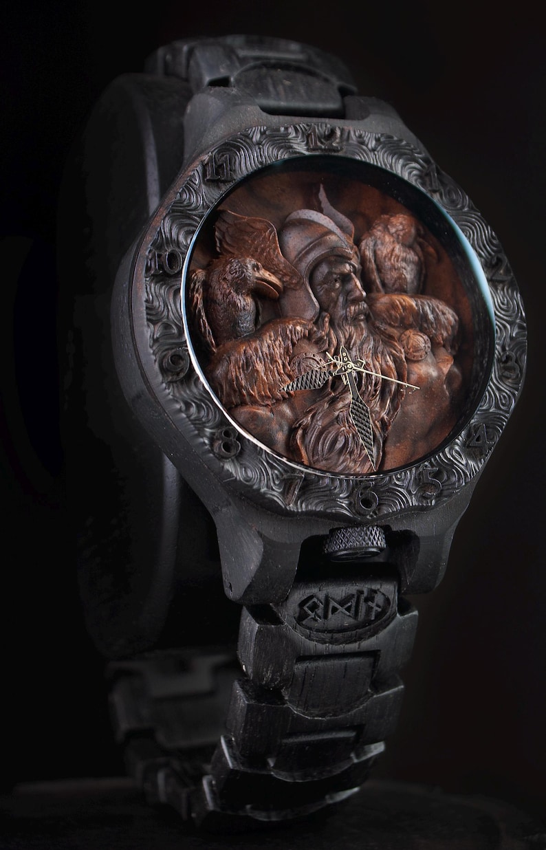 May include: A black wristwatch with a detailed, carved wooden face. The watch face features a relief carving of a bearded figure, birds, and animals. The watch band and case are also black, with intricate designs.