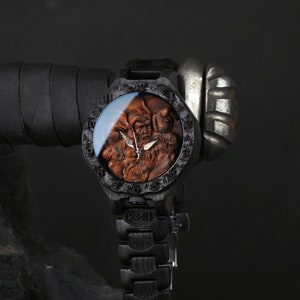 May include: A wooden wristwatch with a detailed carved face featuring a bearded figure. The watch has a dark wood finish, a matching wooden band, and a silver-colored clasp. The watch face is protected by a clear glass cover.