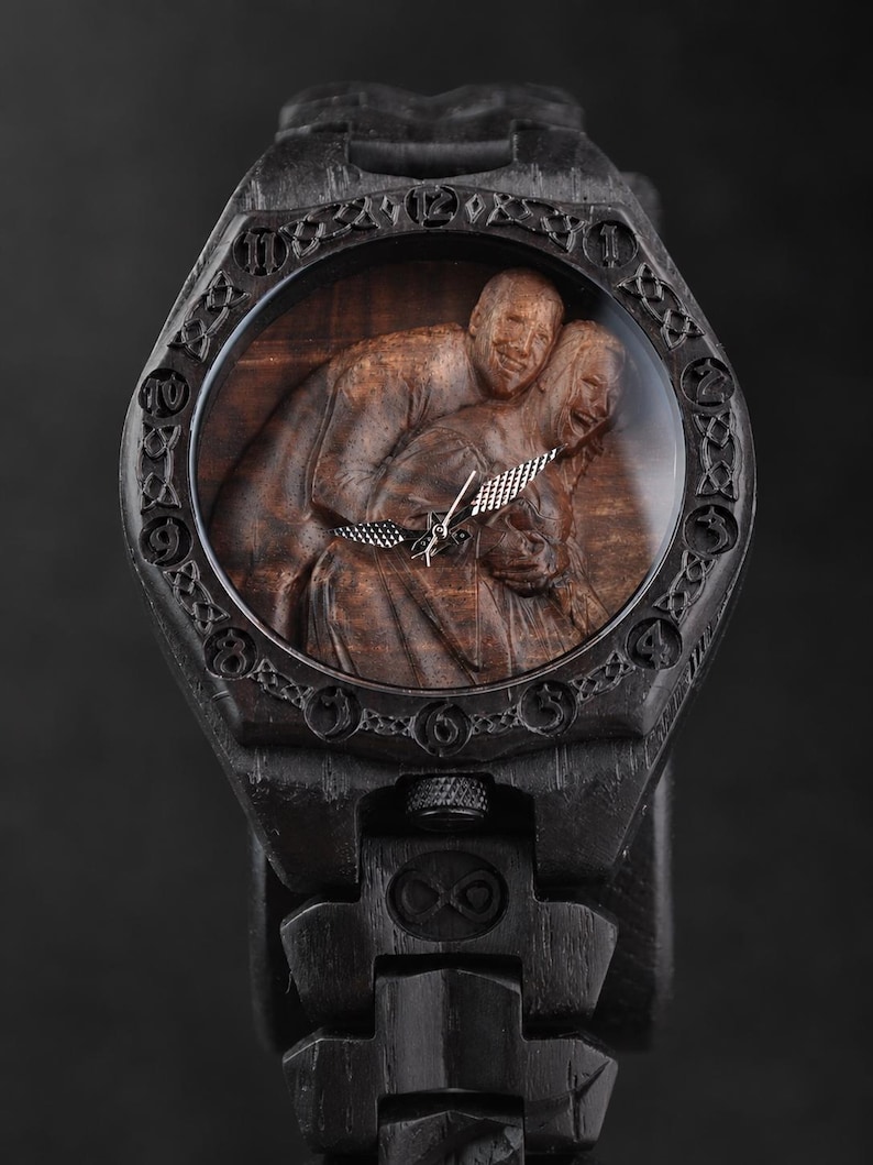 May include: A dark wood wristwatch featuring a carved relief of two people embracing on the dial. The bezel displays engraved numbers and intricate knotwork patterns. The watch includes silver-toned hands and a matching dark wood link bracelet.