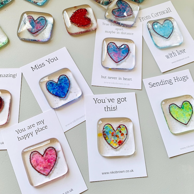 Various glass heart tokens on white cards