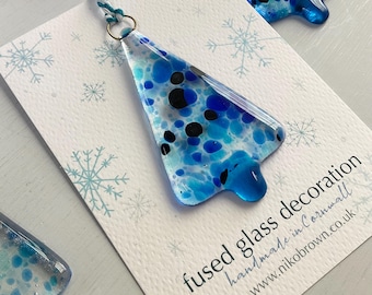 Könnte beinhalten: Ein blauer und weißer Weihnachtsbaum-Anhänger aus geschmolzenem Glas mit schwarzen Punkten. Der Anhänger ist handgefertigt in Cornwall und kann auf der Website www.nikobrown.co.uk erworben werden.