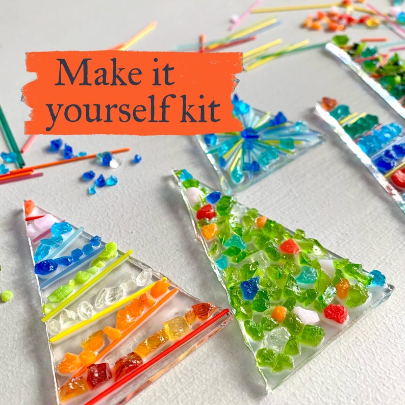 May include: A DIY kit with colorful glass pieces arranged in triangular shapes. The text "Make it yourself kit" is displayed on an orange background. The glass pieces are in shades of blue, green, orange, and red.
