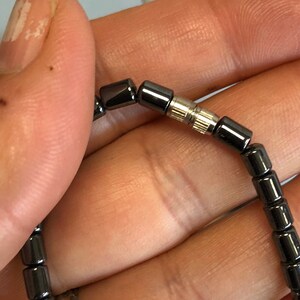 May include: A black beaded bracelet with a silver clasp. The bracelet is made of small, round beads.