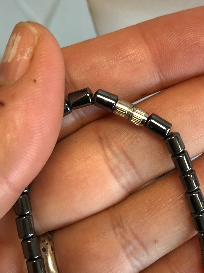May include: A black beaded bracelet with a silver clasp. The bracelet is made of small, round beads.