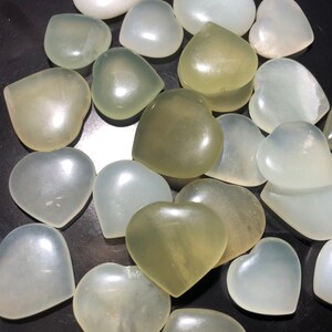 May include: A collection of heart-shaped polished stones in shades of white and green. The stones are smooth and have a natural, organic look.