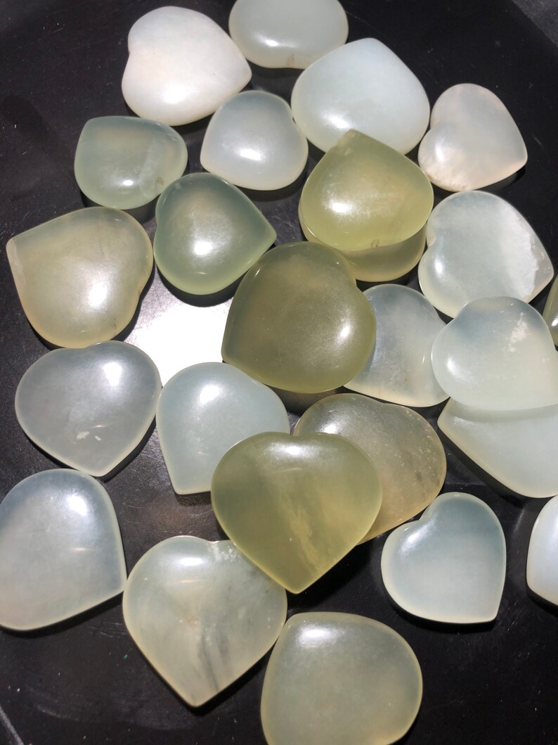 May include: A collection of heart-shaped polished stones in shades of white and green. The stones are smooth and have a natural, organic look.