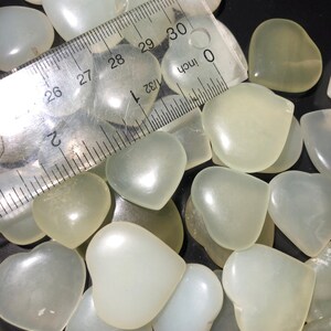May include: A close-up of a pile of white heart-shaped stones. The stones are smooth and polished, and they are arranged in a random pattern. A ruler is visible in the image, with the measurement 30 inches marked.
