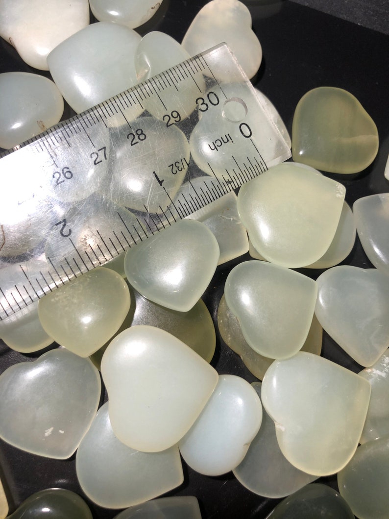 May include: A close-up of a pile of white heart-shaped stones. The stones are smooth and polished, and they are arranged in a random pattern. A ruler is visible in the image, with the measurement 30 inches marked.