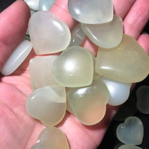 May include: A collection of heart-shaped green jade stones. The stones are smooth and polished, and they have a translucent appearance.