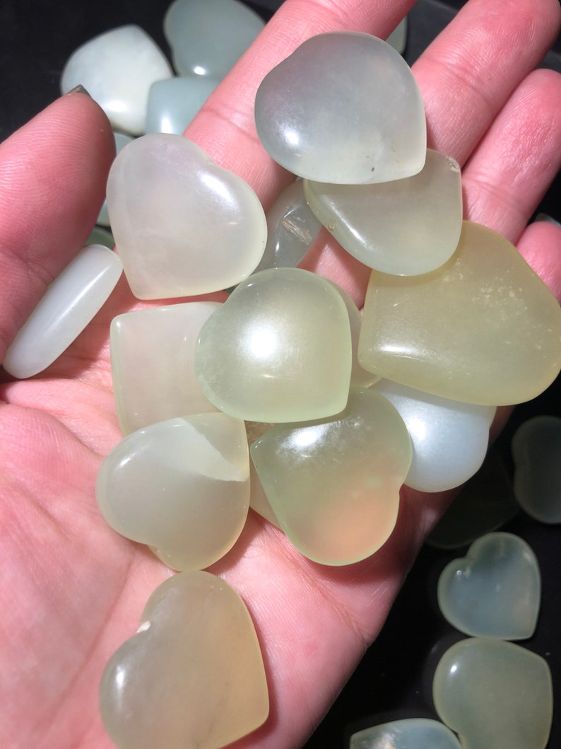 May include: A collection of heart-shaped green jade stones. The stones are smooth and polished, and they have a translucent appearance.