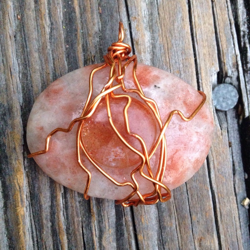 Oval and round sunstone cabochons wrapped with copper wire
