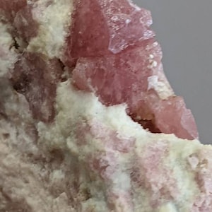 May include: A cluster of pink and white crystals in a rough, natural formation. The crystals are translucent and have a slightly sparkly appearance.