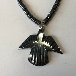 May include: A black hematite necklace with a carved hematite bird pendant. The necklace is made of small, round beads.