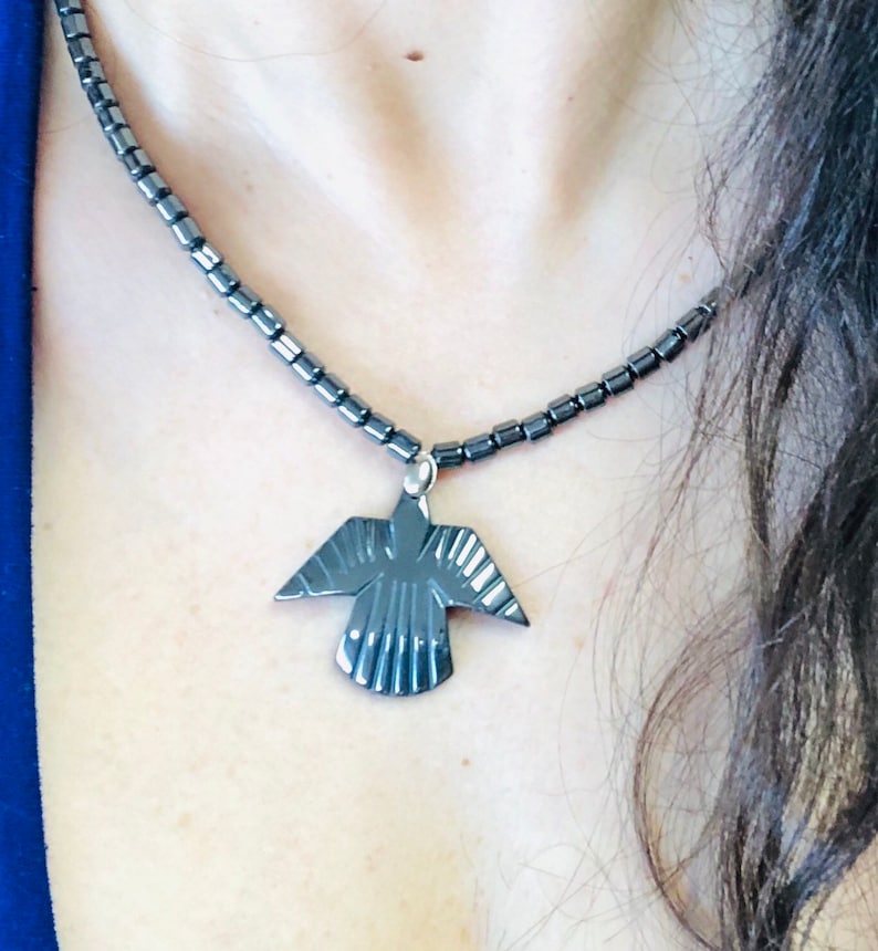 May include: A black necklace with a black bird pendant. The necklace is made of small, round beads.