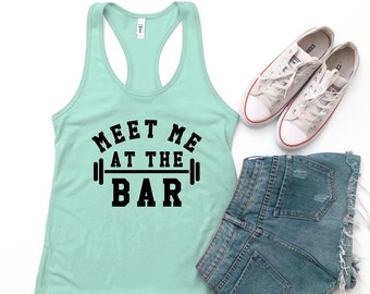 May include: A light blue tank top with a black graphic that says "Meet me at the bar" with a barbell on either side of the word "bar".