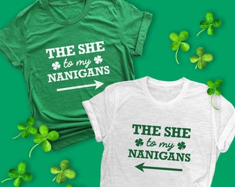 Puede incluir: Dos camisetas verdes y blancas con el texto "The She to my Nanigans" y una flecha apuntando hacia la derecha. Las camisetas están sobre un fondo verde con hojas de trébol.