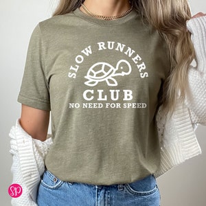 May include: A green t-shirt with a white graphic of a turtle and the text "Slow Runners Club No Need For Speed".