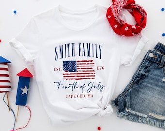 May include: White t-shirt with a distressed American flag graphic and the text "Smith Family Est. 1776 Fourth of July Cape Cod, MA"
