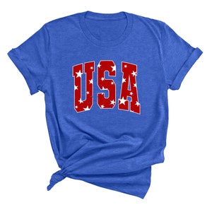 K&ouml;nnte beinhalten: Ein k&ouml;nigsblaues T-Shirt mit einer roten "USA"-Grafik. Die Buchstaben sind mit wei&szlig;en Sternen gef&uuml;llt.