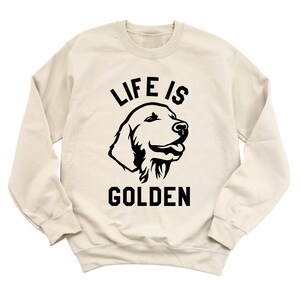 May include: A beige sweatshirt with a black silhouette of a golden retriever and the text "Life is Golden".