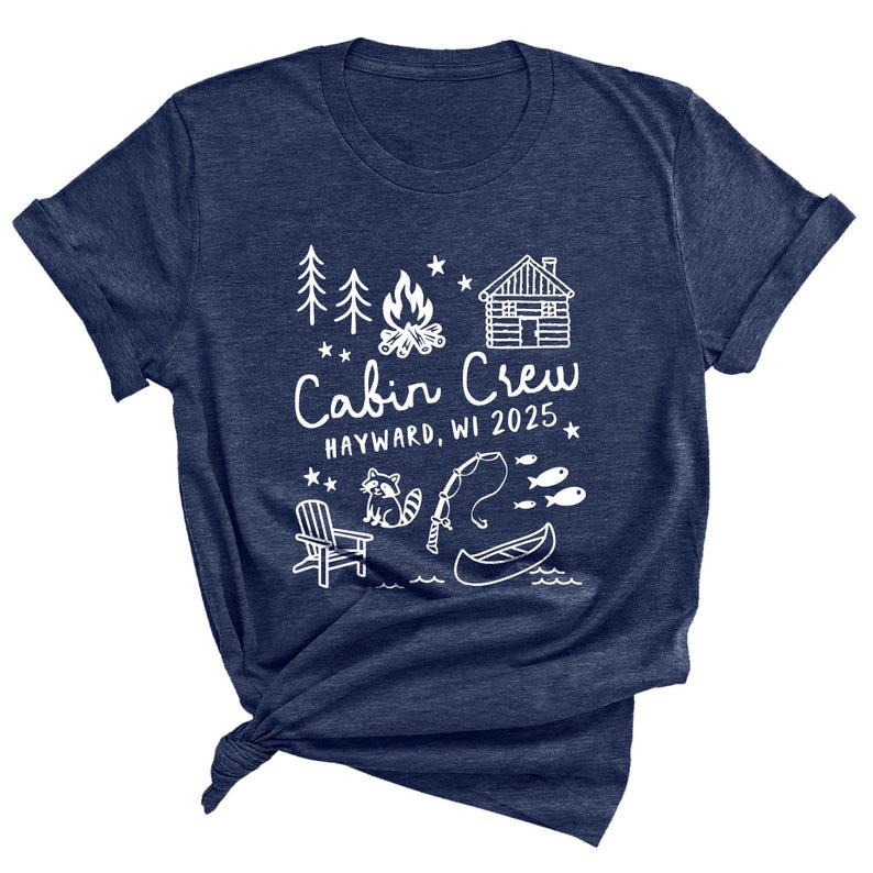 May include: Navy blue t-shirt with a white graphic design. The design includes a cabin, campfire, trees, raccoon, fishing rod, canoe, and the text "Cabin Crew 2025, Hayward, WI". A casual tee for outdoor enthusiasts.