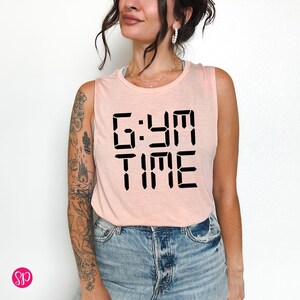 May include: A pink sleeveless tank top with the text "GYM TIME" in a black digital clock font.