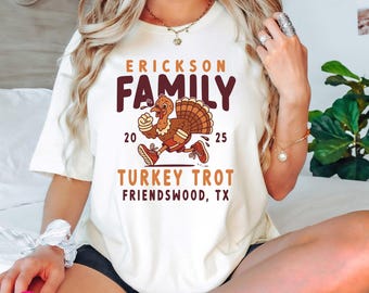 May include: Cream-colored t-shirt featuring the text "ERICKSON FAMILY" above a cartoon turkey running in red sneakers. The shirt also includes "20 25" and "TURKEY TROT FRIENDSWOOD, TX" in a playful font.