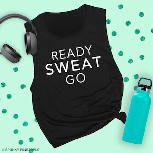 May include: Black sleeveless workout tank top with the text "READY SWEAT GO" in white. The tank top is on a light green background with green confetti.
