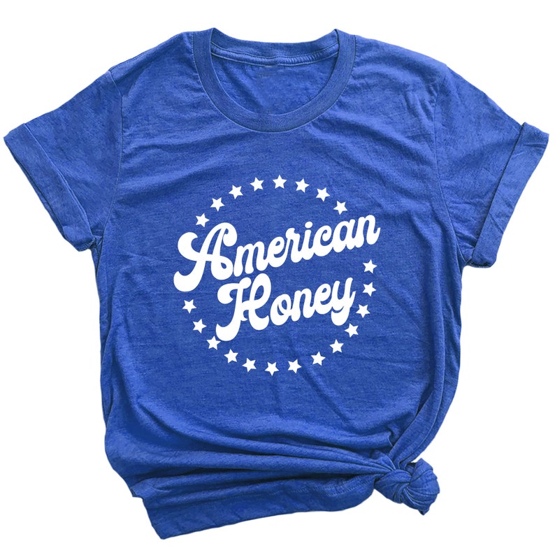 K&ouml;nnte beinhalten: Ein k&ouml;nigsblaues T-Shirt mit einem wei&szlig;en Kreisdesign, das den Text "American Honey" in einer Retro-Schriftart zeigt, umgeben von wei&szlig;en Sternen.