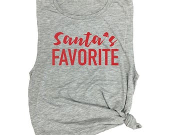 May include: A heather gray sleeveless muscle tank top featuring the red text Santa's FAVORITE printed on the front. The word Santa's is written in a cursive script with a small red hat icon, while FAVORITE is in bold block letters.