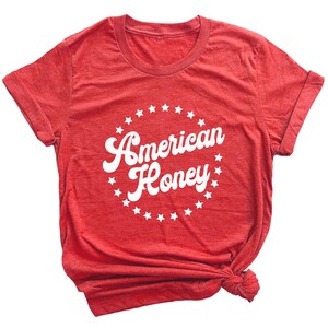 K&ouml;nnte beinhalten: Rotes T-Shirt mit einem wei&szlig;en Kreisdesign mit Sternen und dem Text "American Honey".
