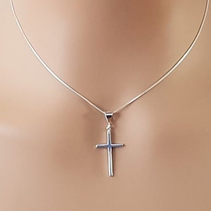 May include: A silver chain necklace with a simple silver cross pendant.