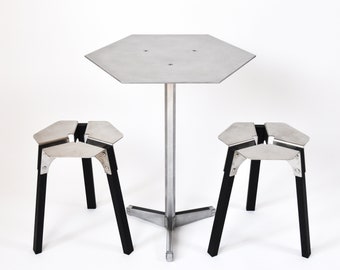 May include: A silver hexagonal table with a silver pedestal base and two black metal stools. The stools have a unique, geometric design.