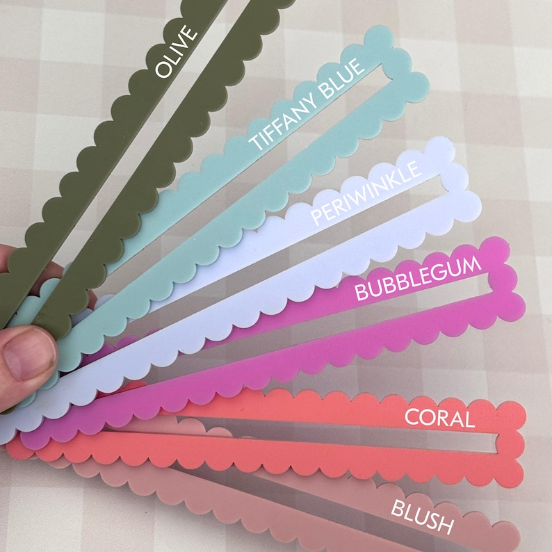 May include: A selection of coloured swatches with a scalloped edge, held in a hand. The colours are olive, Tiffany blue, periwinkle, bubblegum, coral, and blush, each labelled with its name in white text.
